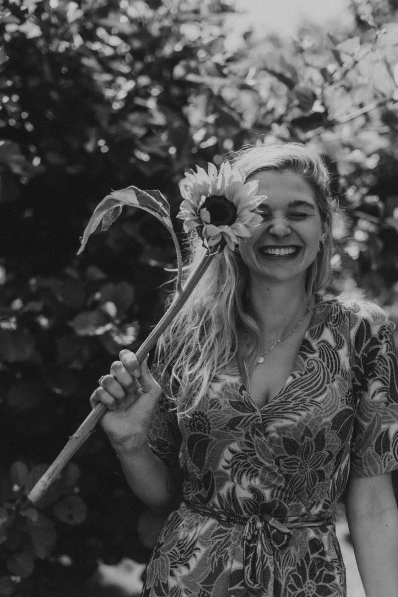 Nienke lacht met een zonnebloem in haar hand
